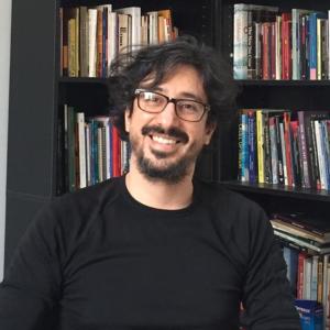 Jaime Vargas-Luna smiling in front on a bookshelf.